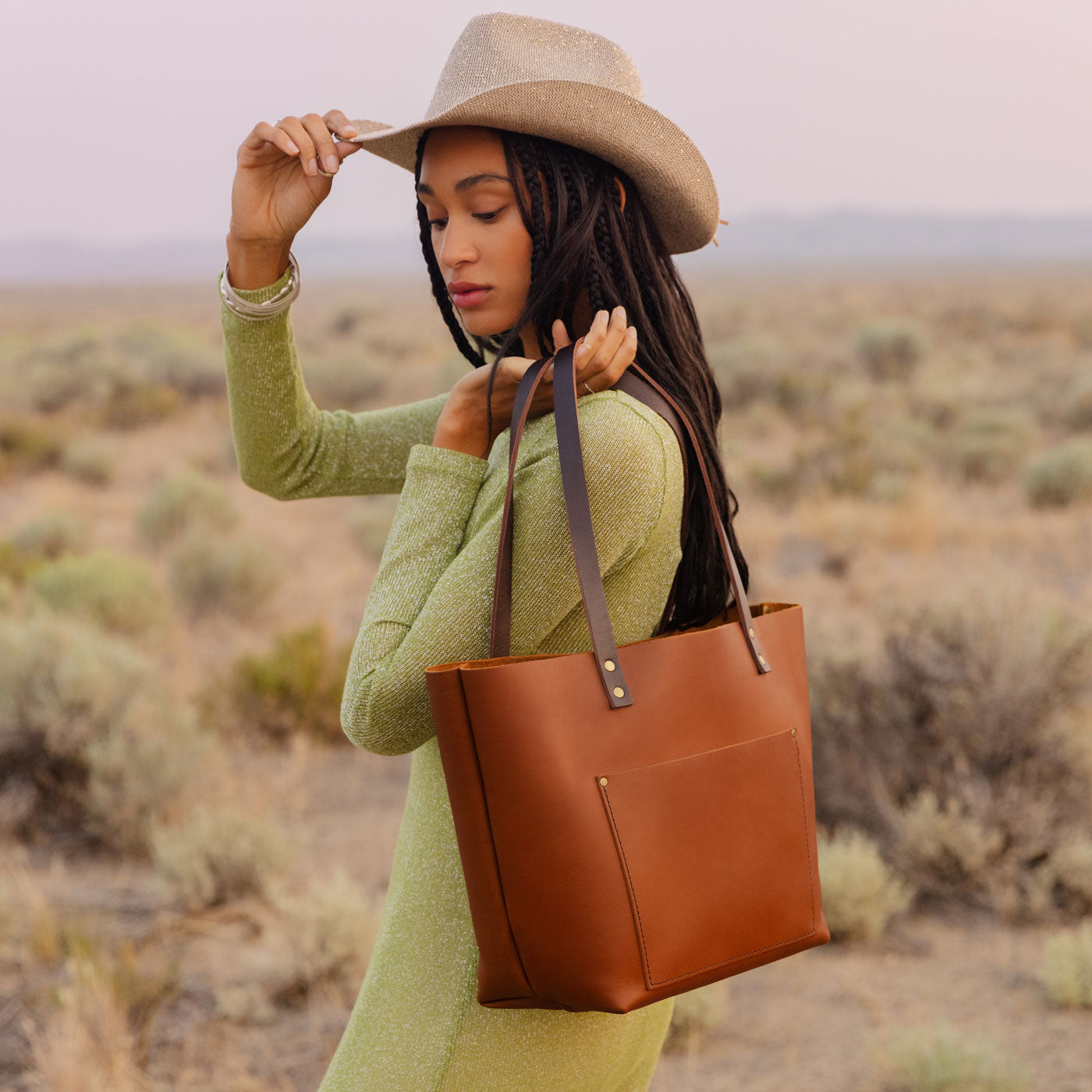 Honey | Model wearing larger leather tote bag with sturdy bridle handles and front pocket outside