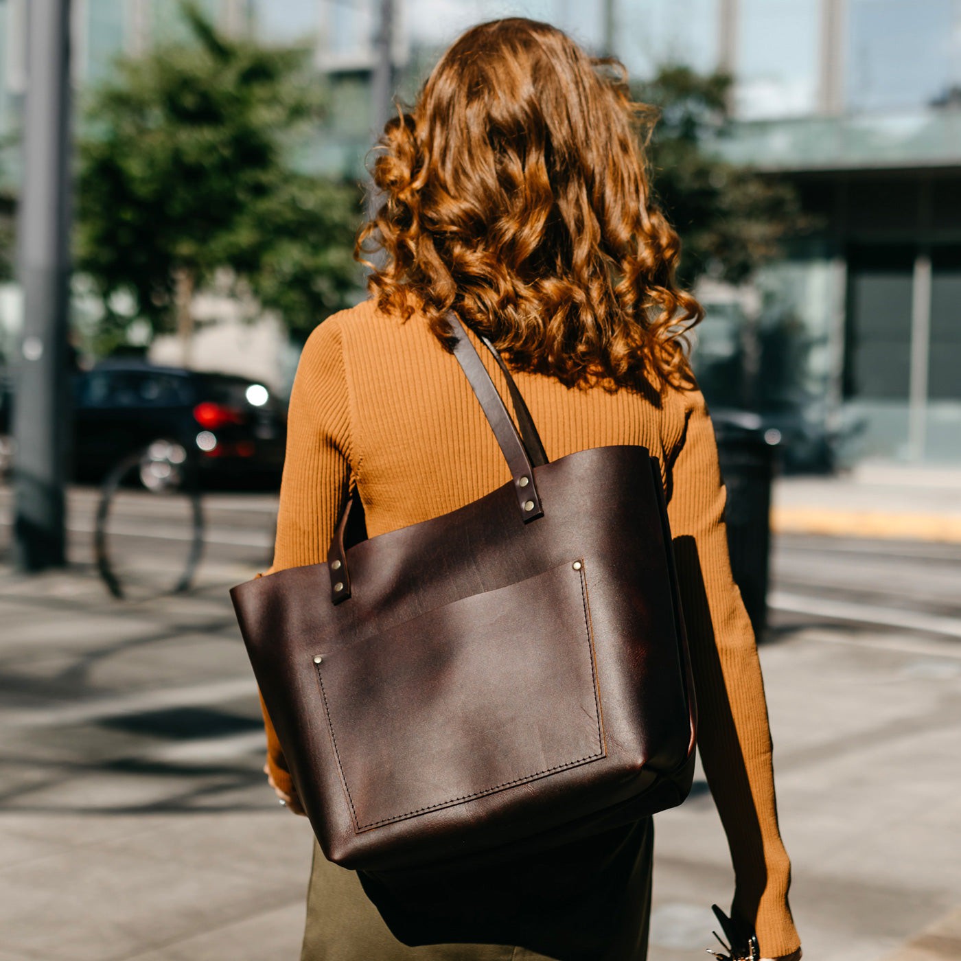 Grizzly | Model wearing larger leather tote bag with sturdy bridle handles and front pocket outside