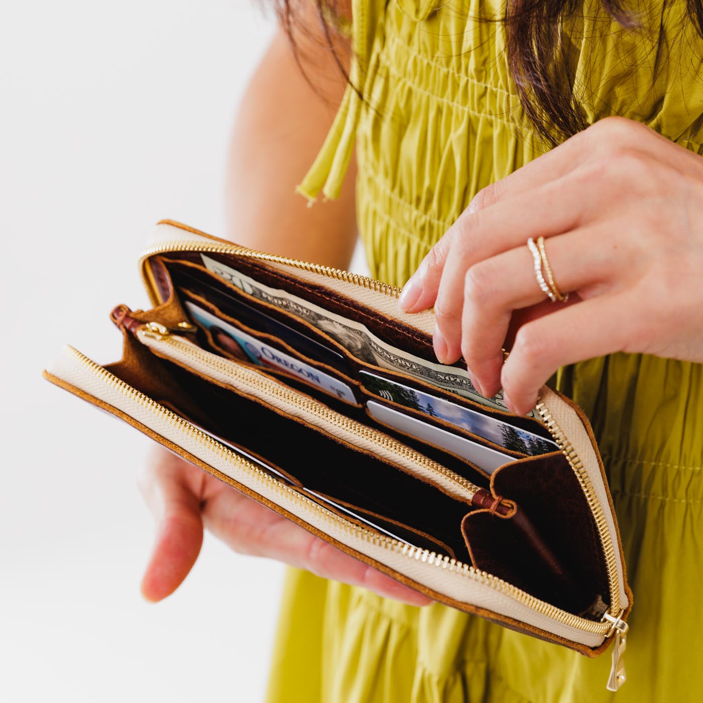 Cinnamon Bear | Model holding large accordion leather wallet with zipper open