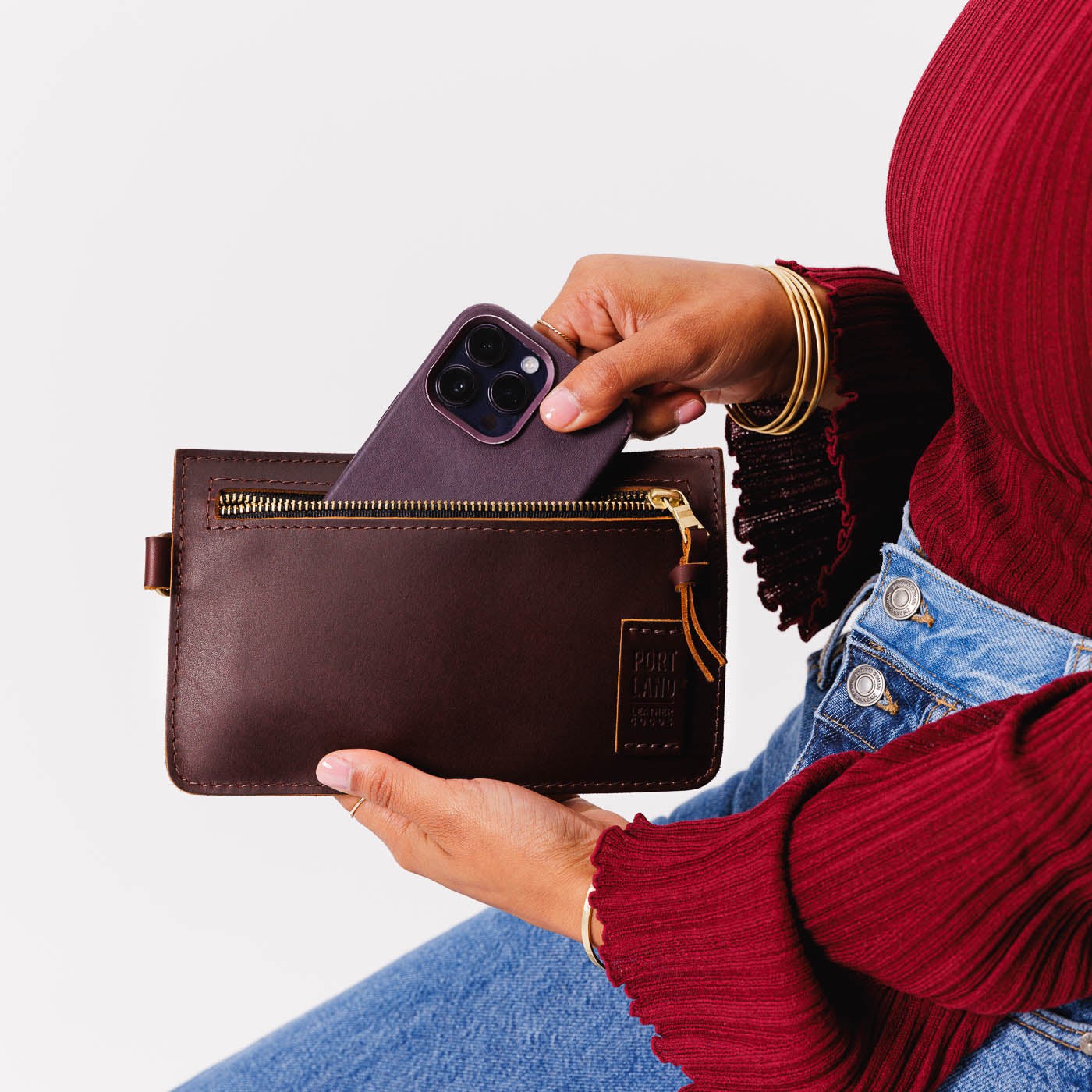 Cognac | Model holding flat leather pouch with zipper and wristlet