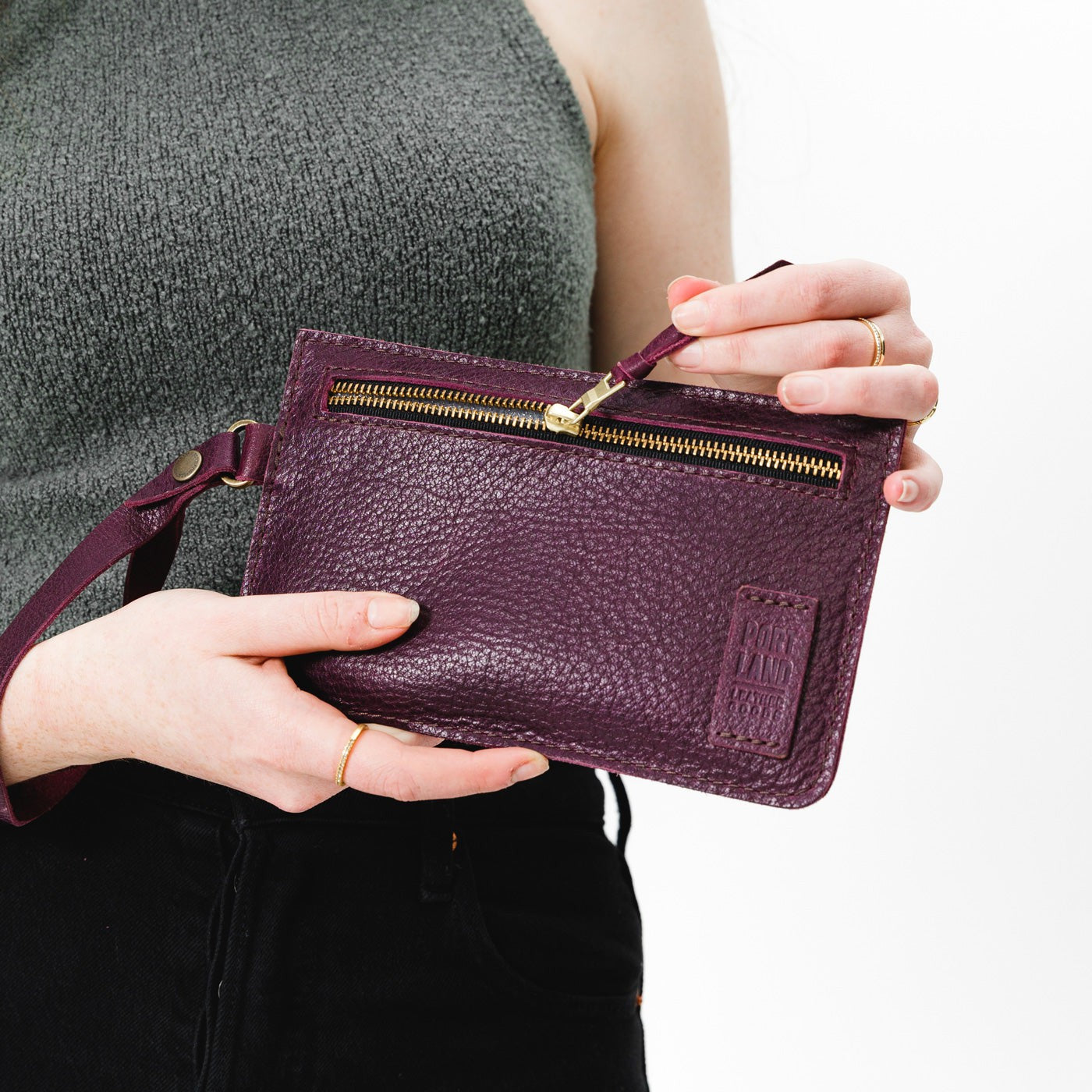 Plum | Model holding flat leather pouch with zipper and wristlet