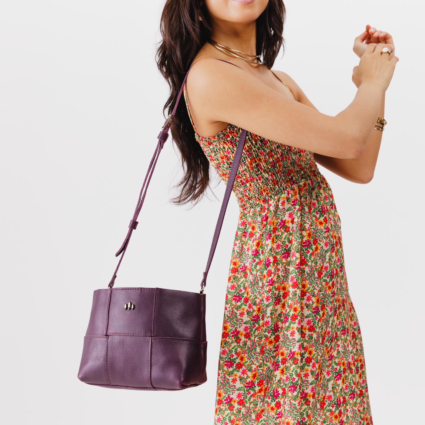 Plum*Small | Model carrying structured woven leather bag with three metal tree emblems and crossbody strap