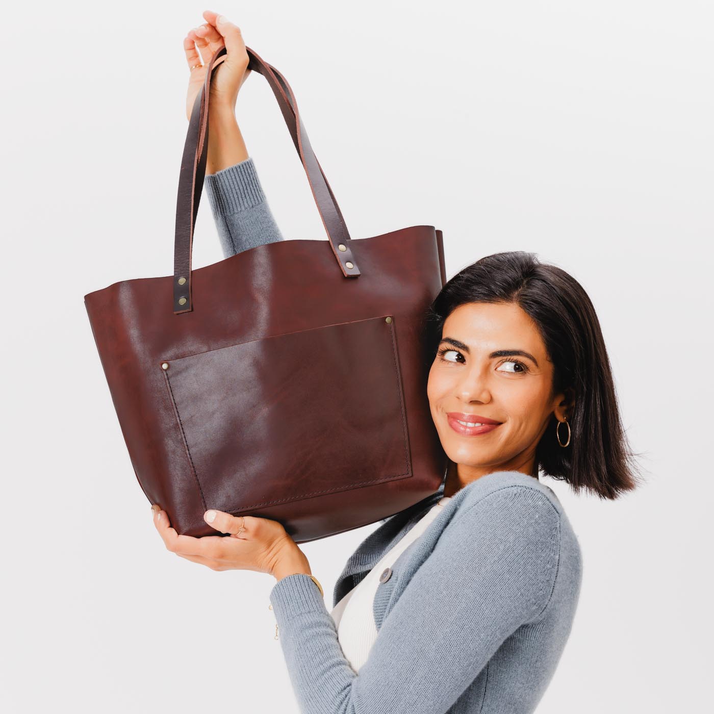 Cognac Classic | Model holding large leather tote bag with sturdy bridle handles and front pocket