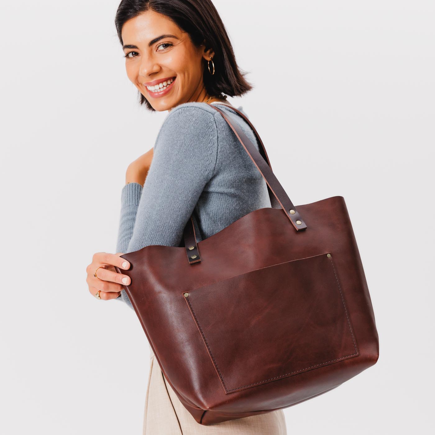 Cognac*Classic | Model holding large leather tote bag with sturdy bridle handles and front pocket