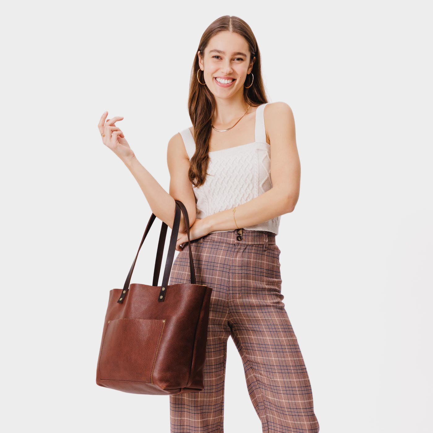 Nutmeg Classic | Model holding large leather tote bag with sturdy bridle handles and front pocket