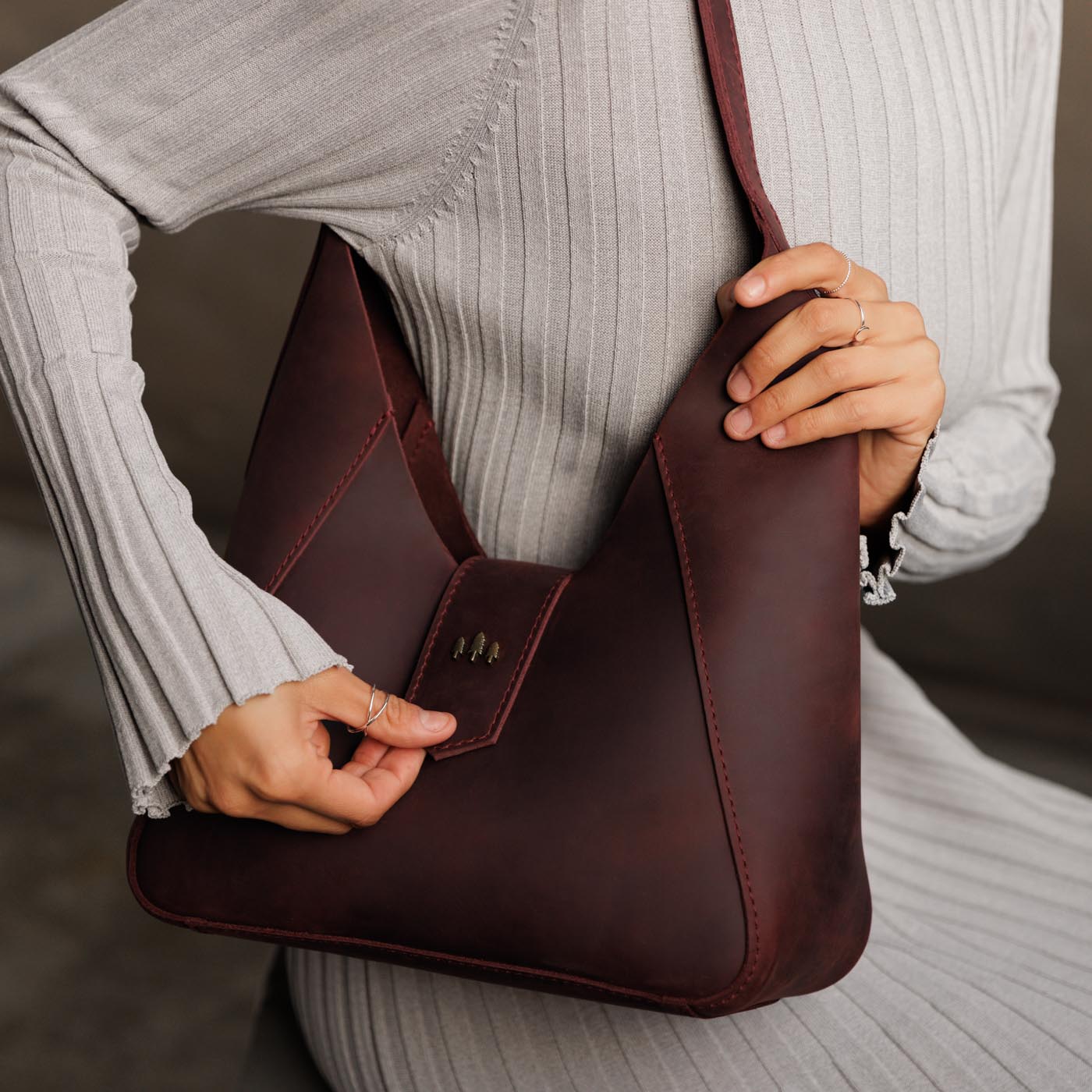 Merlot | Model holding structured hobo shoulder bag with adjustable strap and magnetic closure