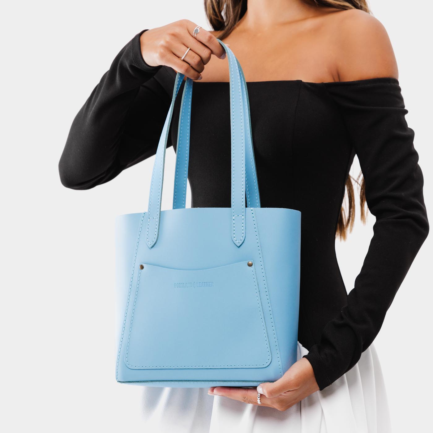 Glacial Blue Small | Model holding dual shoulder strap tote bag with an exterior pocket