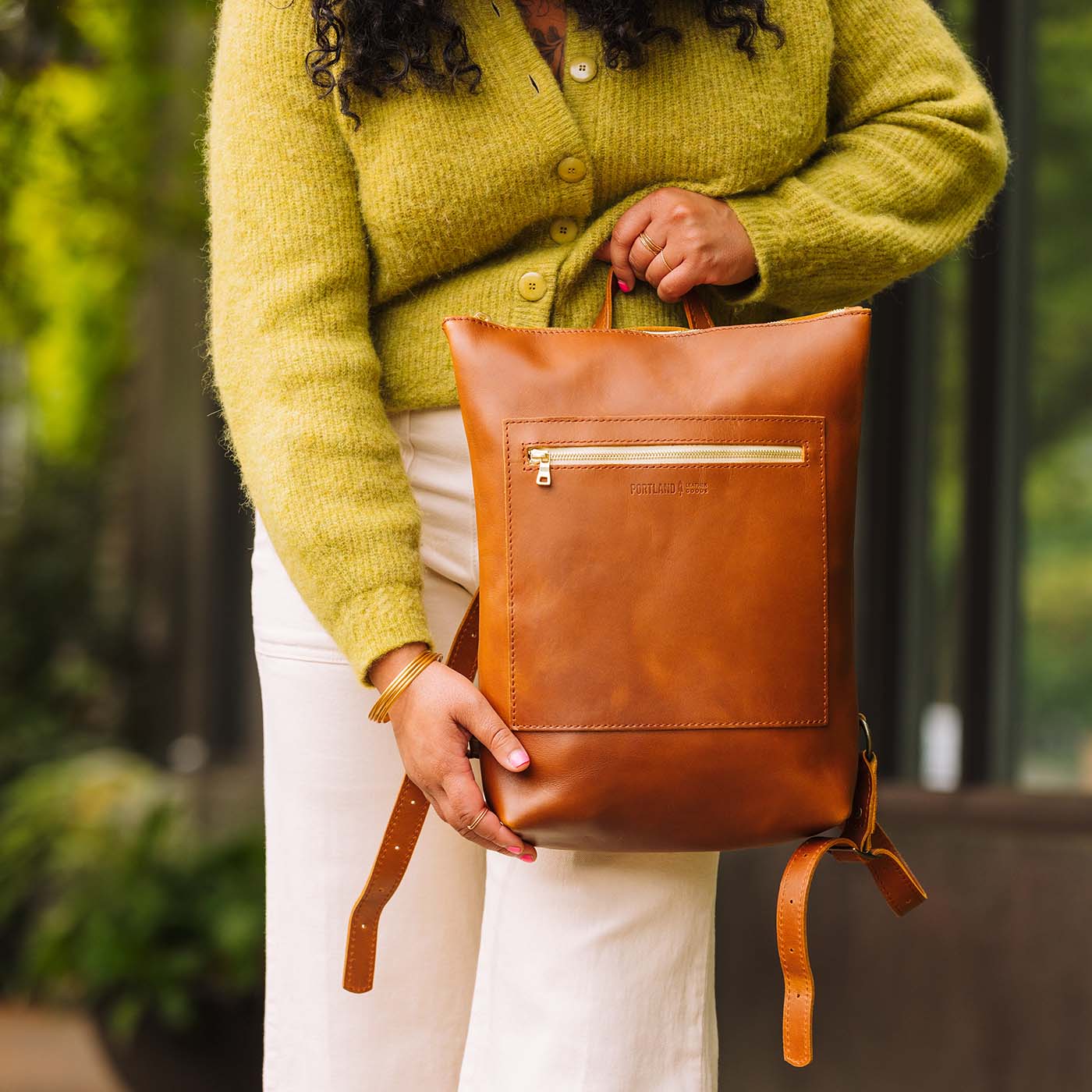 All Color: Honey | Model holding rectangular slim leather backpack