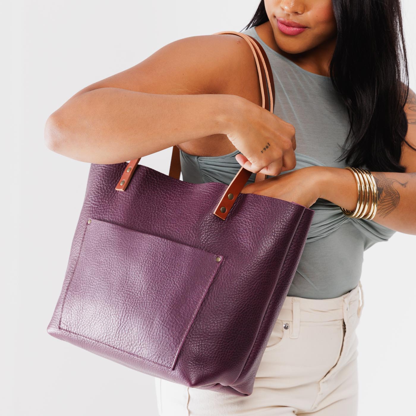 Plum*Classic | Model holding large leather tote bag with sturdy bridle handles and front pocket