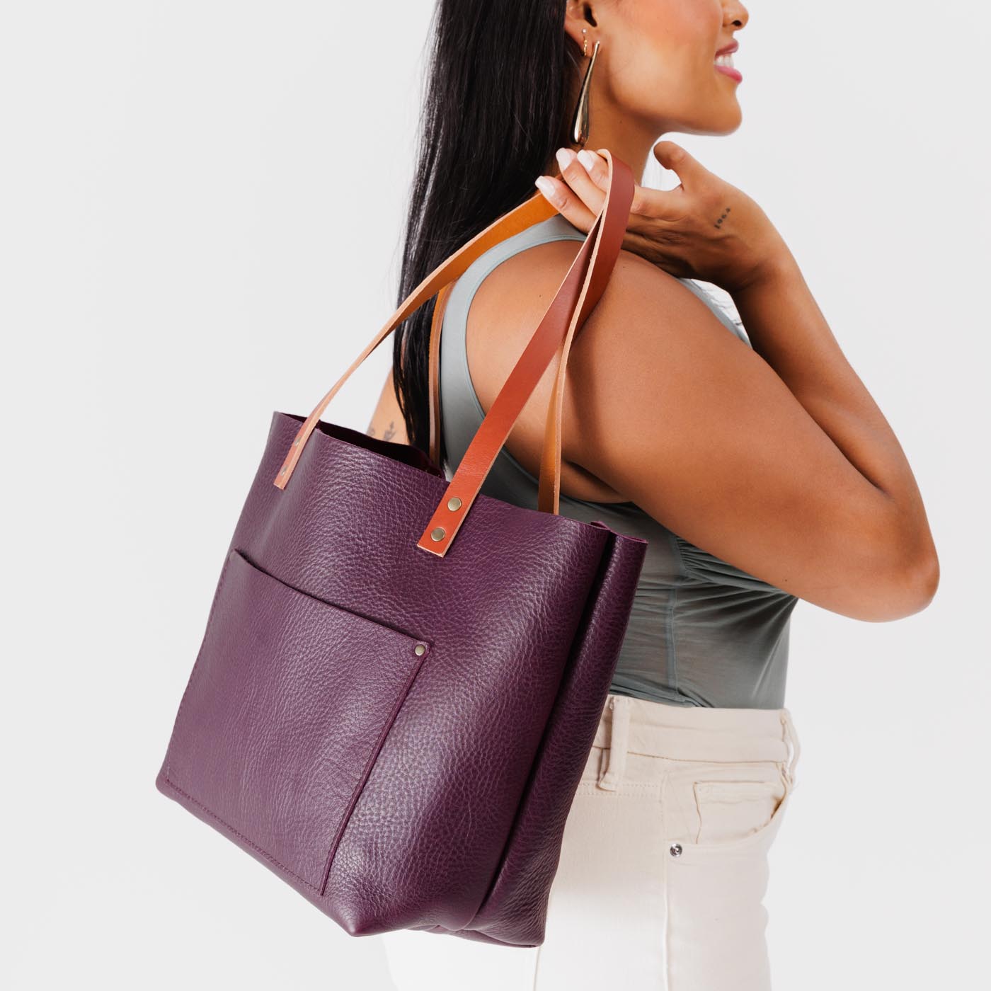 Plum*Classic | Model holding large leather tote bag with sturdy bridle handles and front pocket