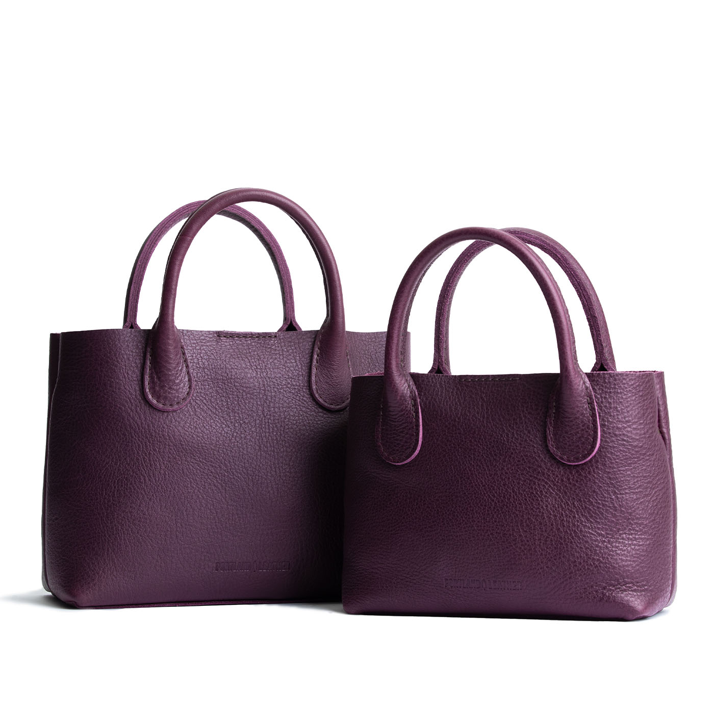 Plum | Side by side of both tote purses with structured leather handles and crossbody strap