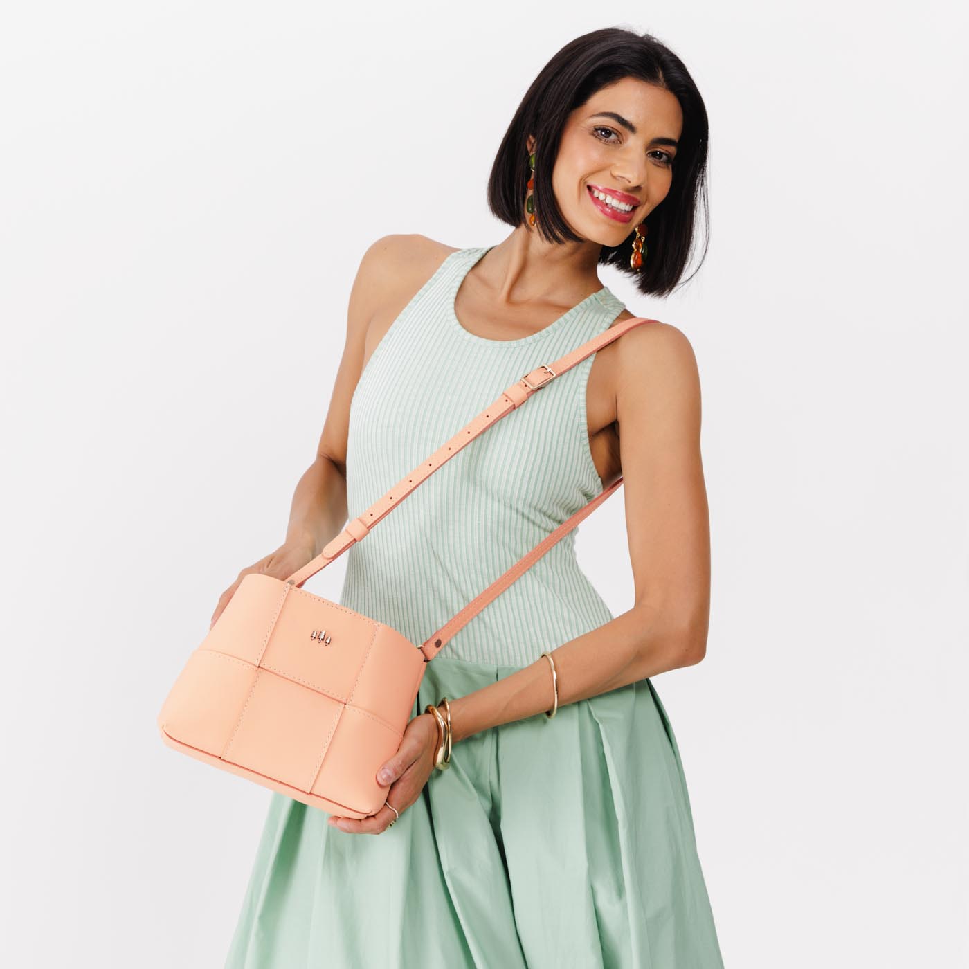 Mamey Small | Model carrying structured woven leather bag with three metal tree emblems and crossbody strap