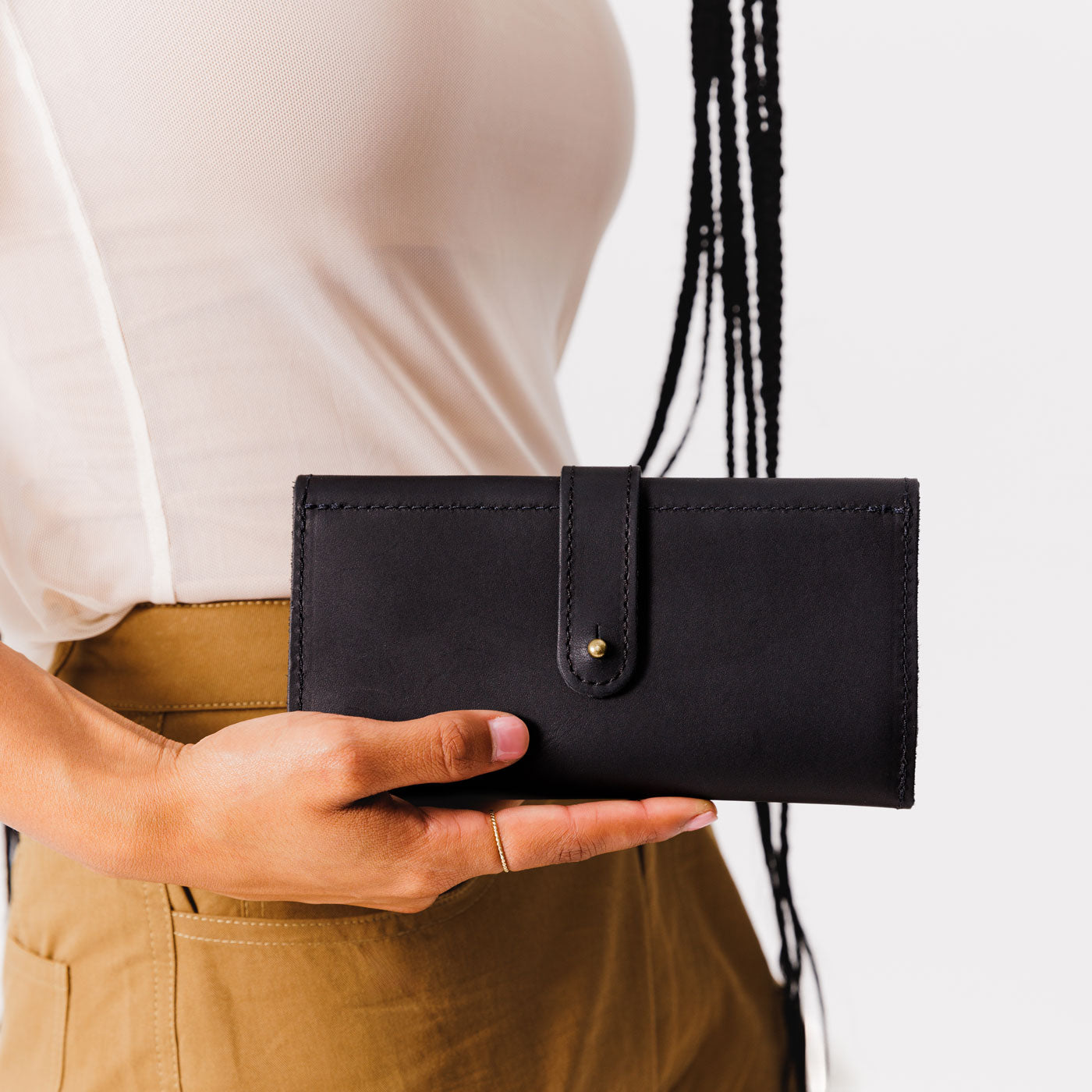 Black | Model holding leather wallet with Sam Browne closure