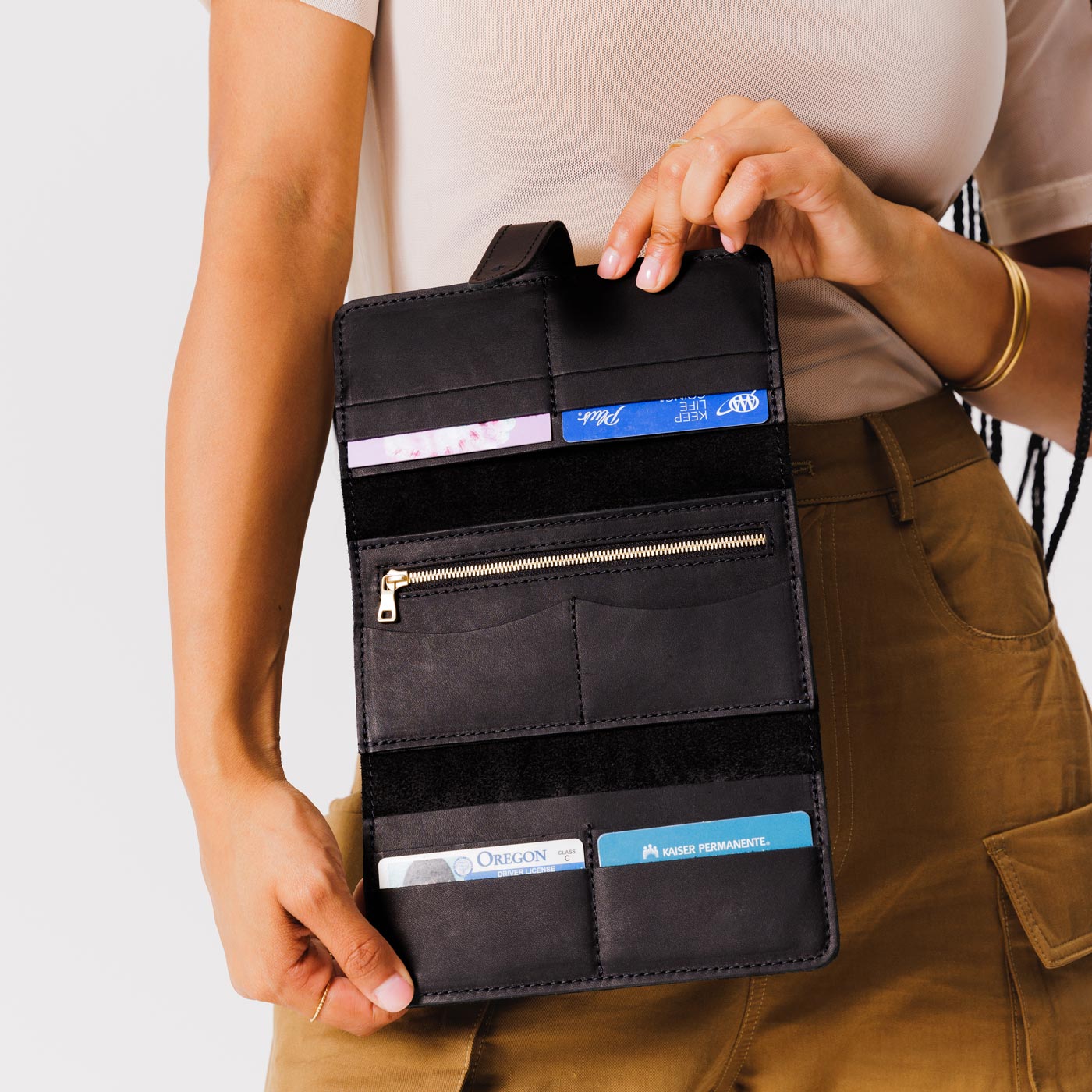 Black | Model holding leather wallet with Sam Browne closure open