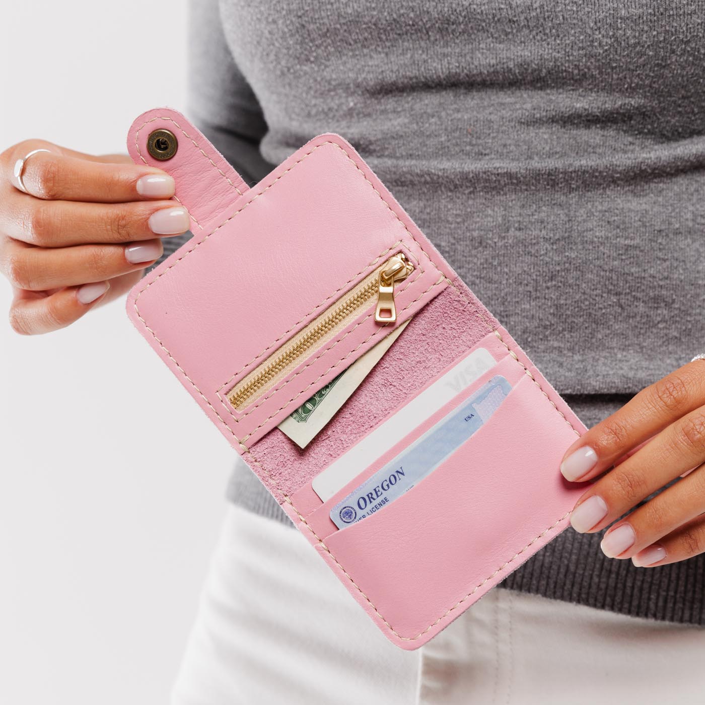 Vintage Pink | Model holding small leather bifold wallet with snap open