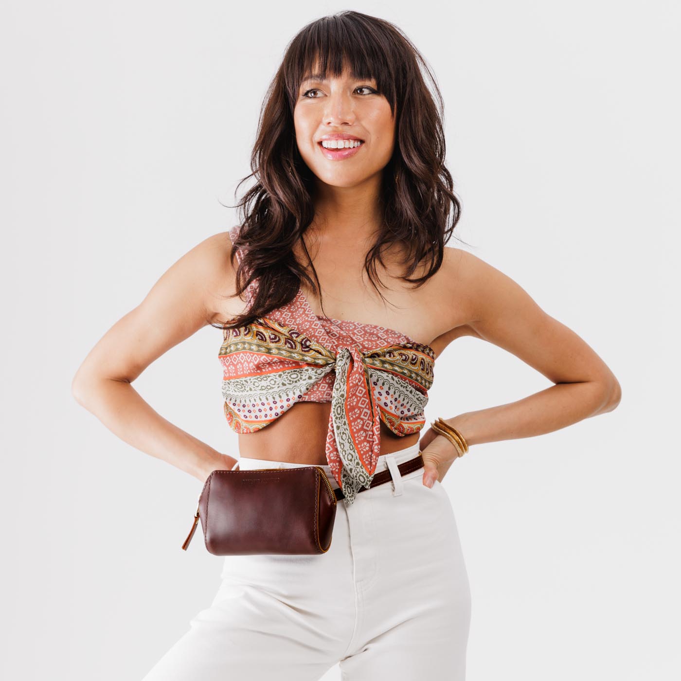  Cognac  | Model wearing petite bag with top zipper closure and adjustable belt strap on waist