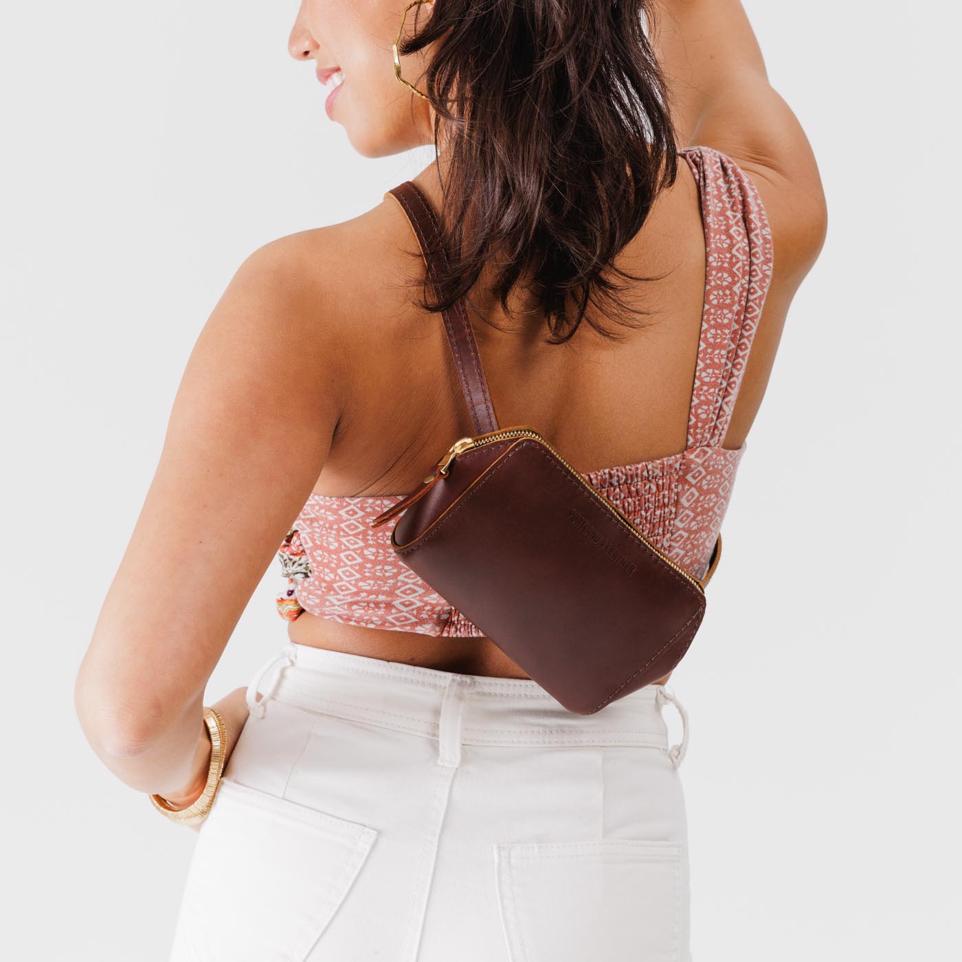 Cognac | Model wearing petite bag with top zipper closure and adjustable belt strap on the back crossbody style