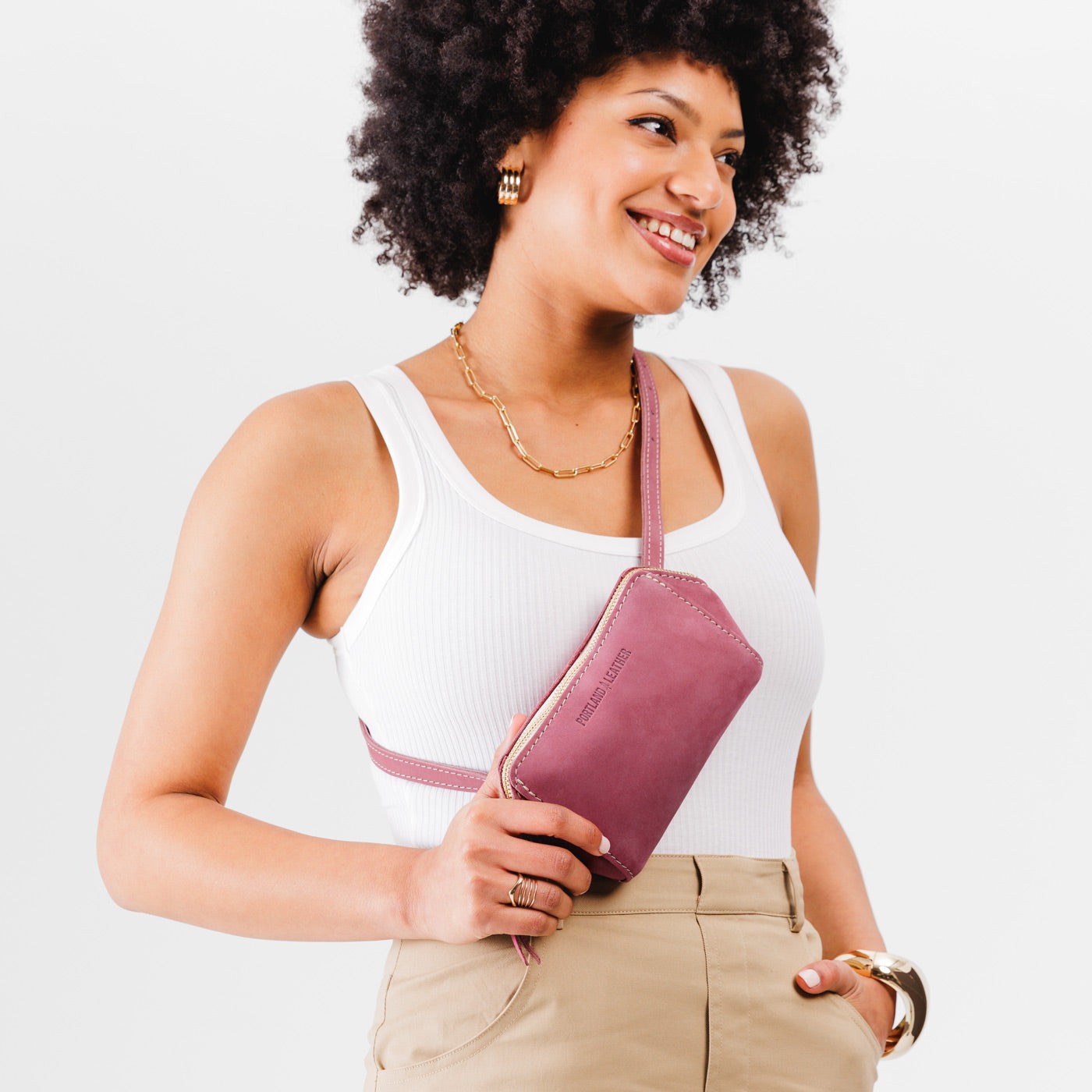  Foxglove | Close up of model wearing petite bag with top zipper closure and adjustable belt strap on the front crossbody style