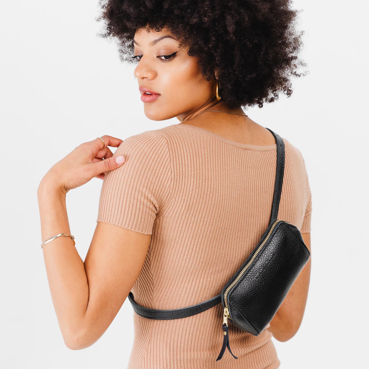 Pebbled--black| Model wearing petite bag with top zipper closure and adjustable belt strap on the back