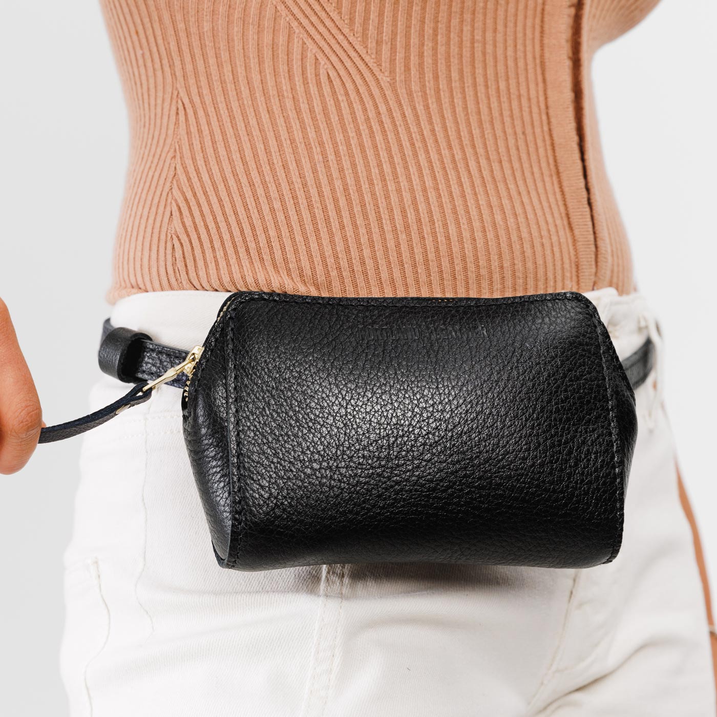 Pebbled--black | Close up of model wearing petite bag with top zipper closure and adjustable belt strap on the waist