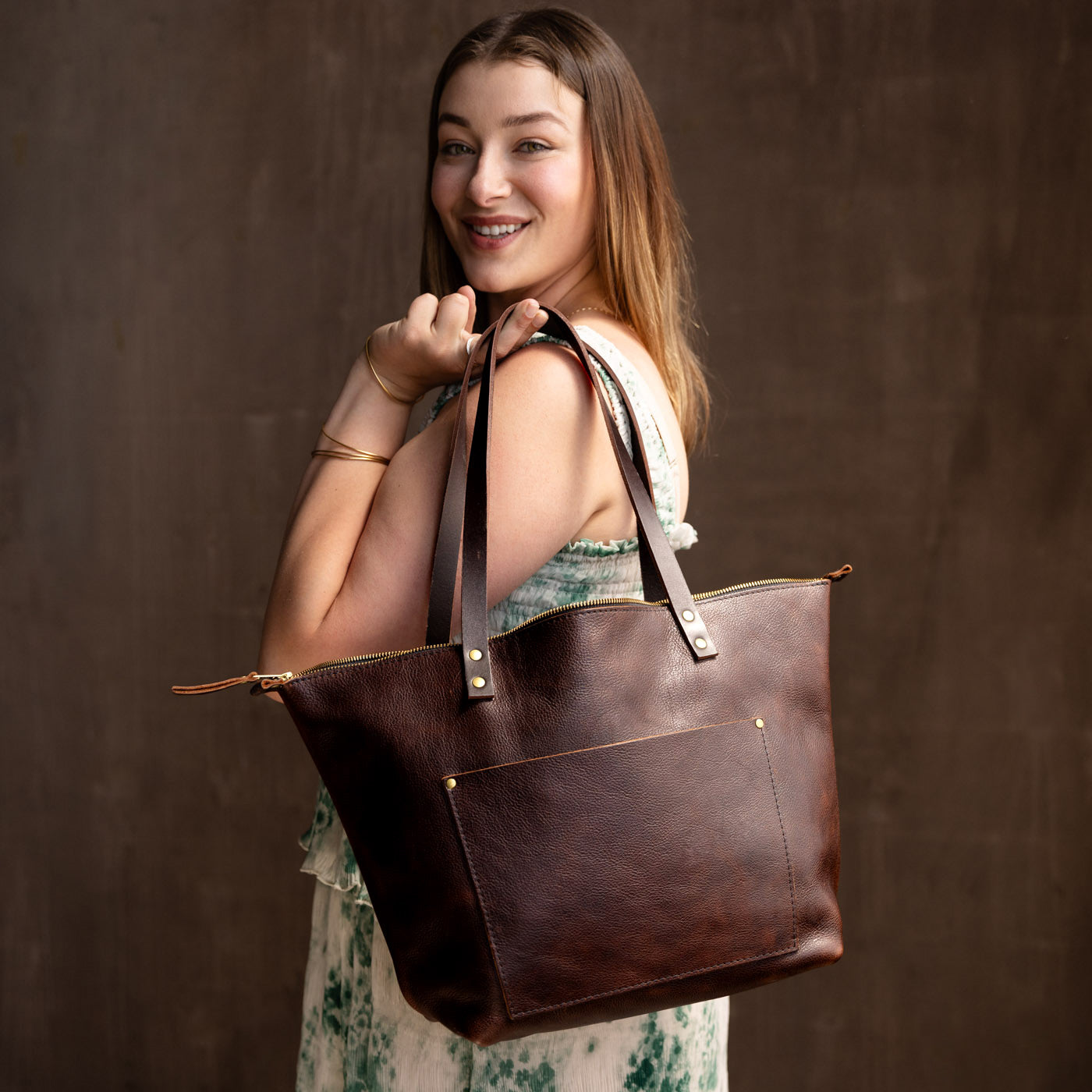 Coldbrew*Zipper | Model holding large zipper leather tote bag with sturdy bridle handles and front pocket