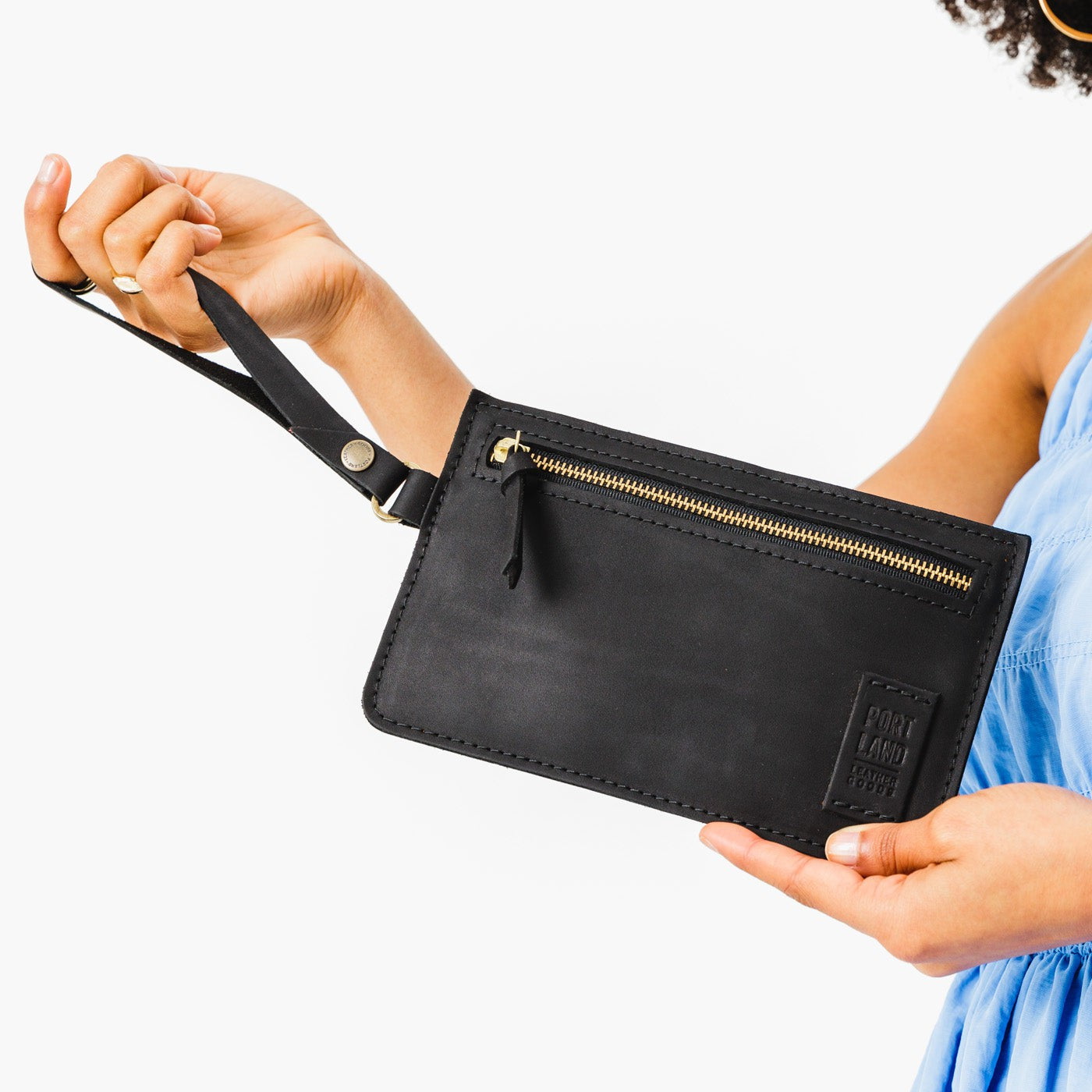 Black | Model holding flat leather pouch with zipper and wristlet