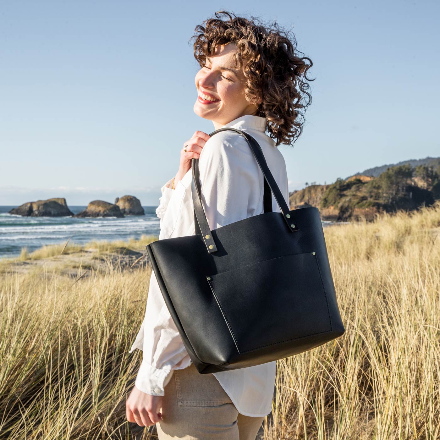 Black  | Model wearing larger leather tote bag with sturdy bridle handles and front pocket outside