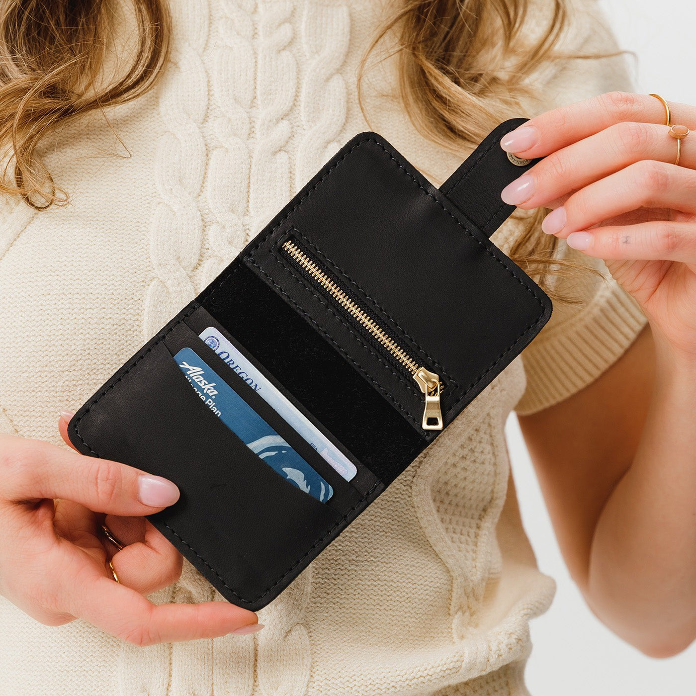 Black | Model holding small leather bifold wallet with snap open