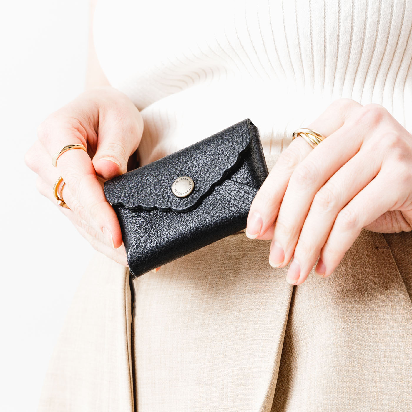 Pebbled--black | Model holding small leather wallet with scalloped edge