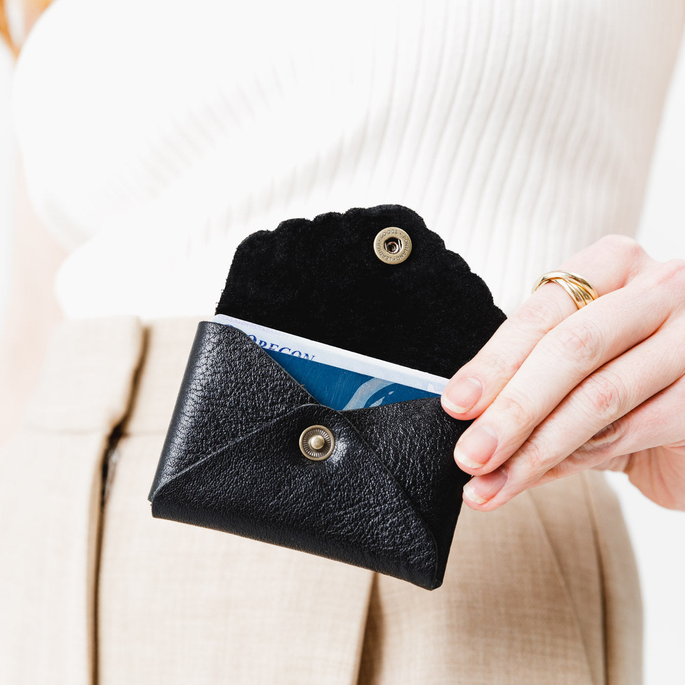 Pebbled--black | Model holding small leather wallet with scalloped edge open