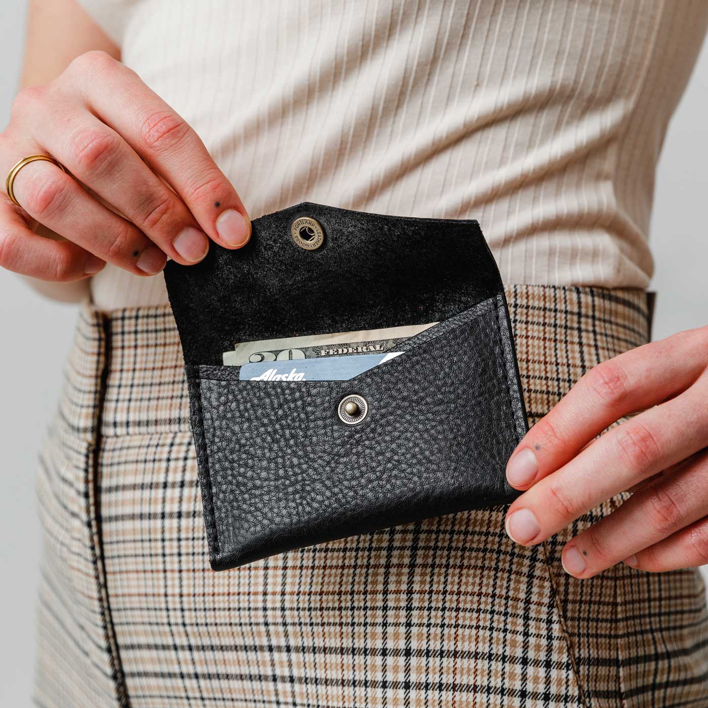 Pebbled--black | Model holding small leather envelope wallet with snap closure open