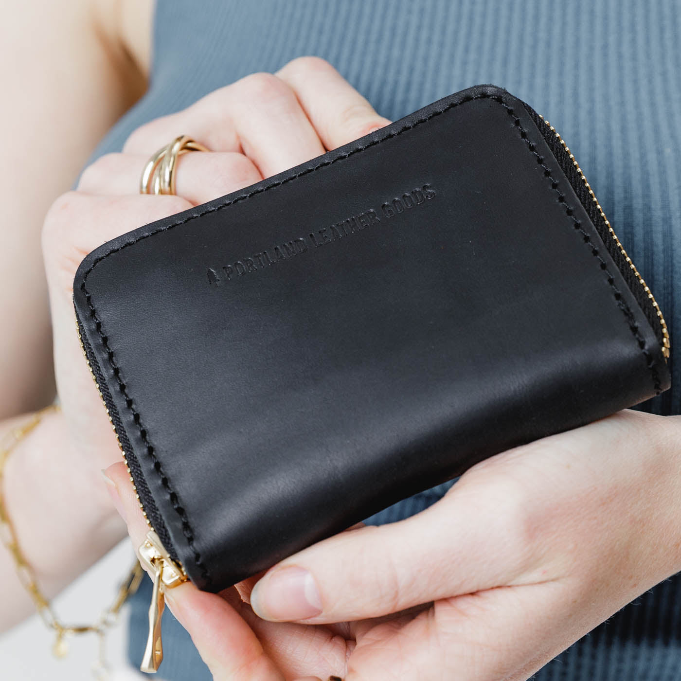 Black | Model holding small leather wallet with zipper closed