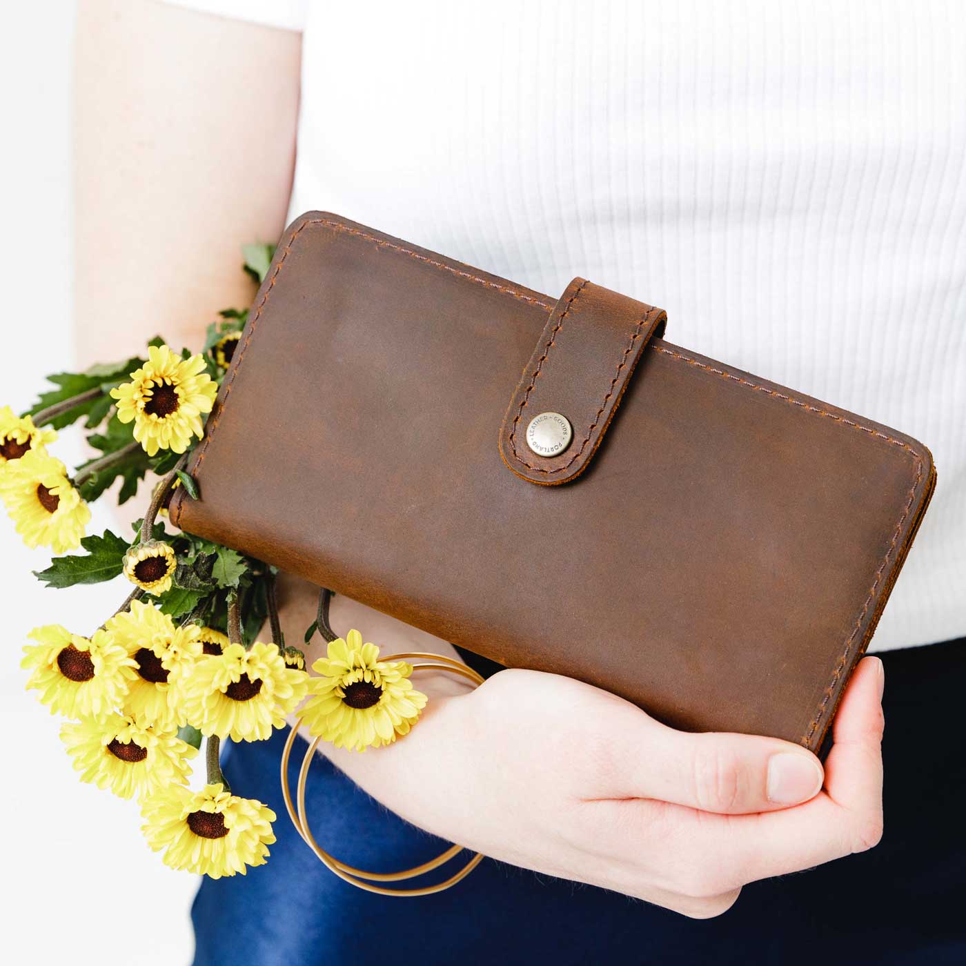 Canyon | Model holding flowers and leather wallet with snap closed