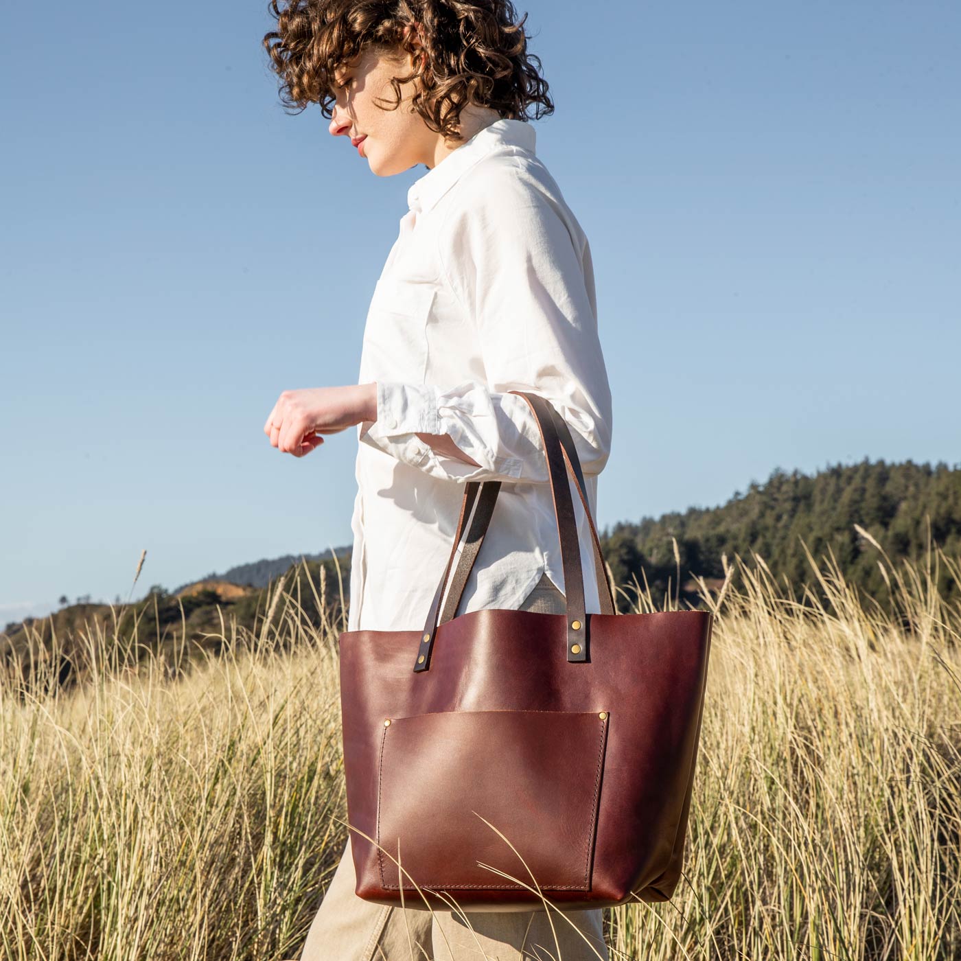 Cognac*Classic | Model wearing larger leather tote bag with sturdy bridle handles and front pocket outside