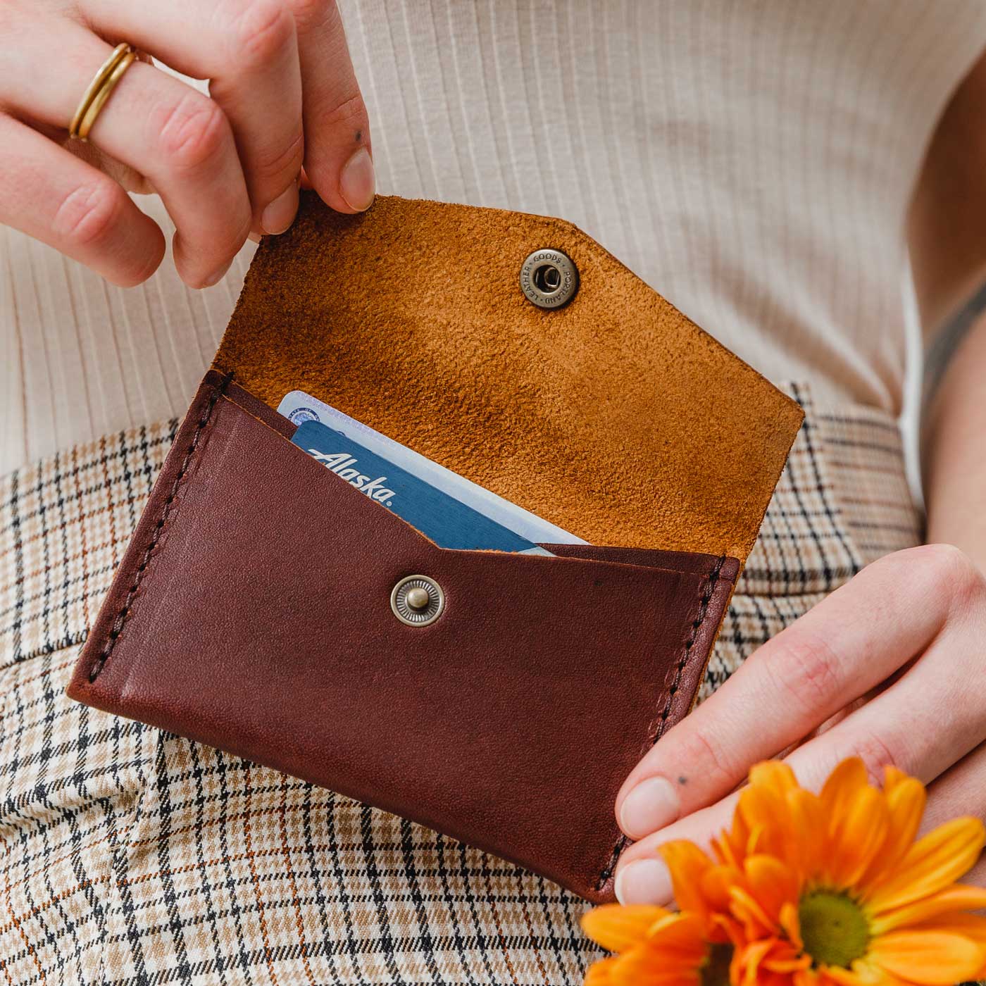 Cognac | Model holding small leather envelope wallet with snap closure open