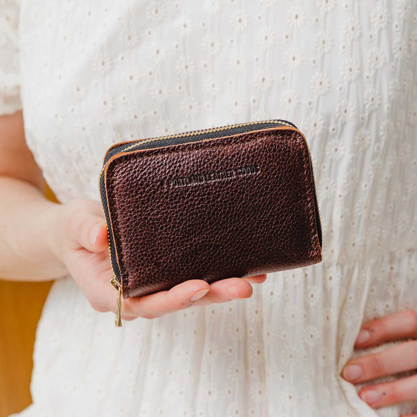 Coldbrew | Model holding small leather wallet with zipper closed