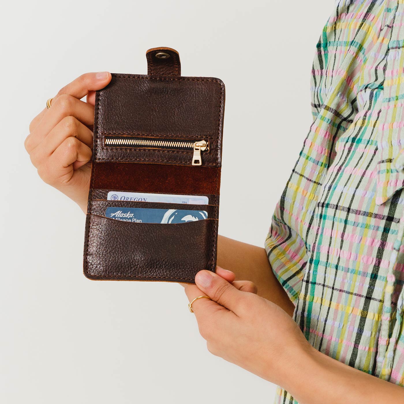 Coldbrew | Model holding small leather bifold wallet with snap open