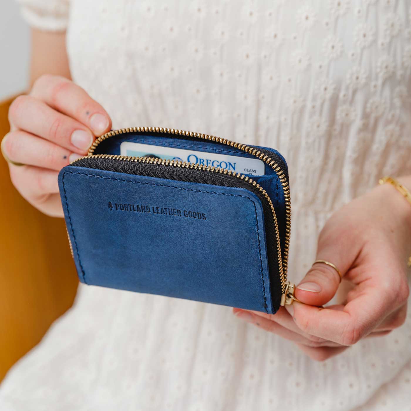 Deep Water | Model holding small leather wallet with zipper open