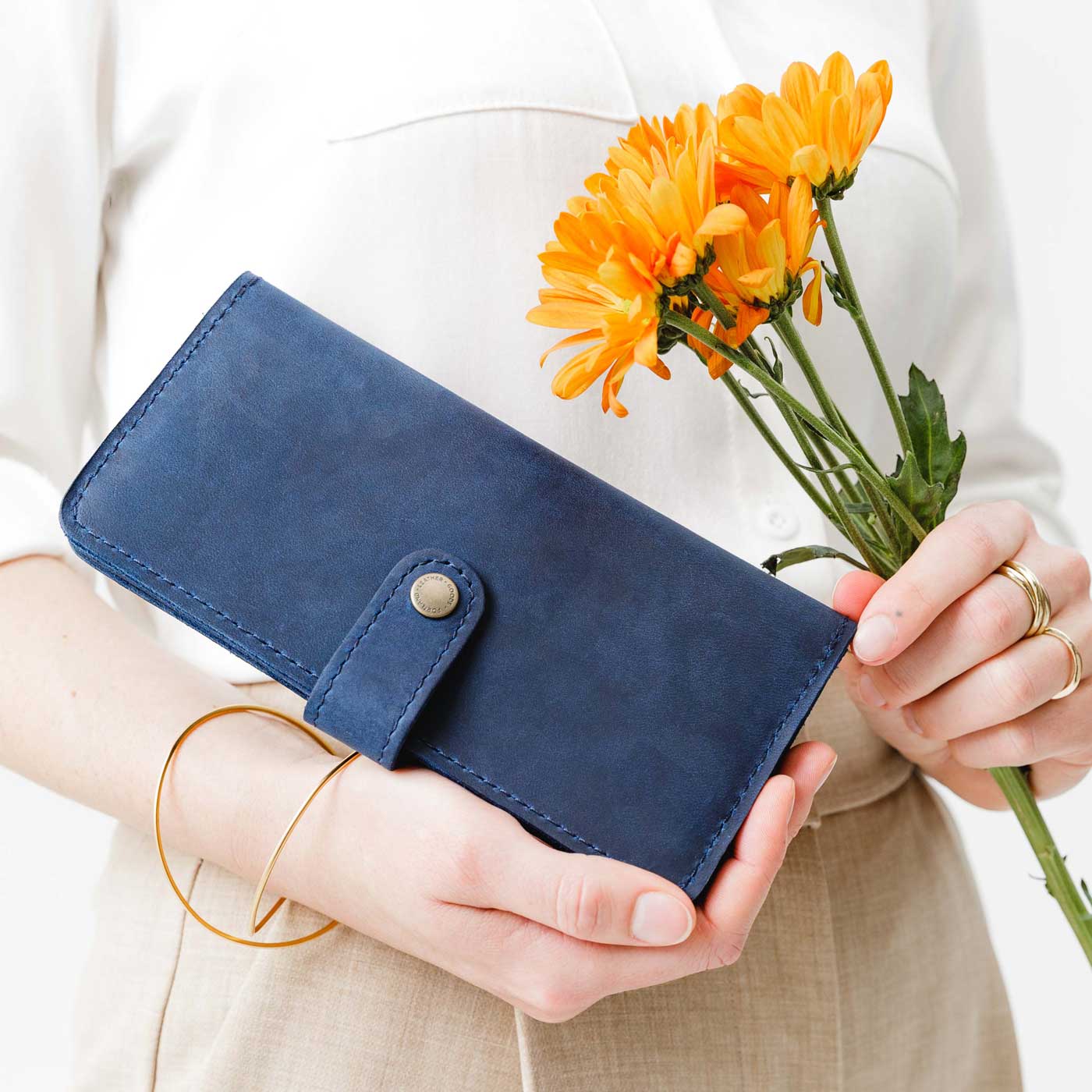 Deep Water | Model holding flowers and leather wallet with snap closed