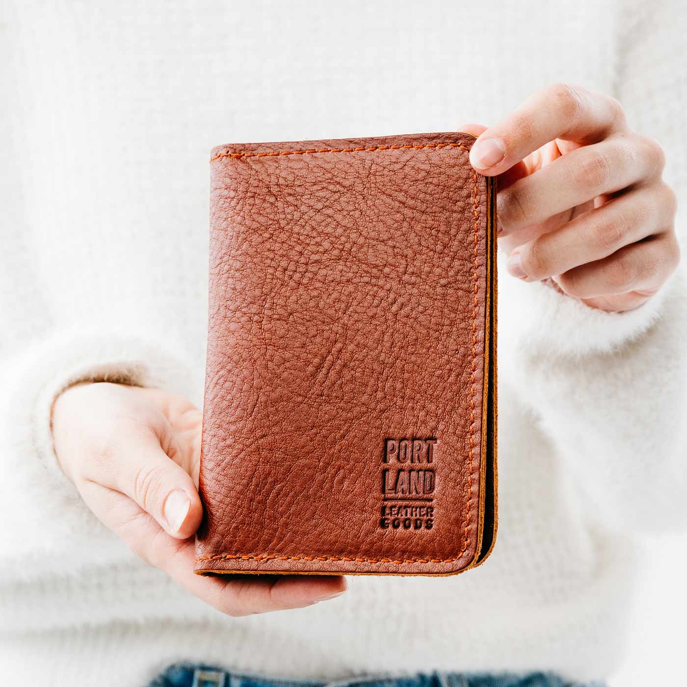 Nutmeg | Model holding leather passport case with PLG logo