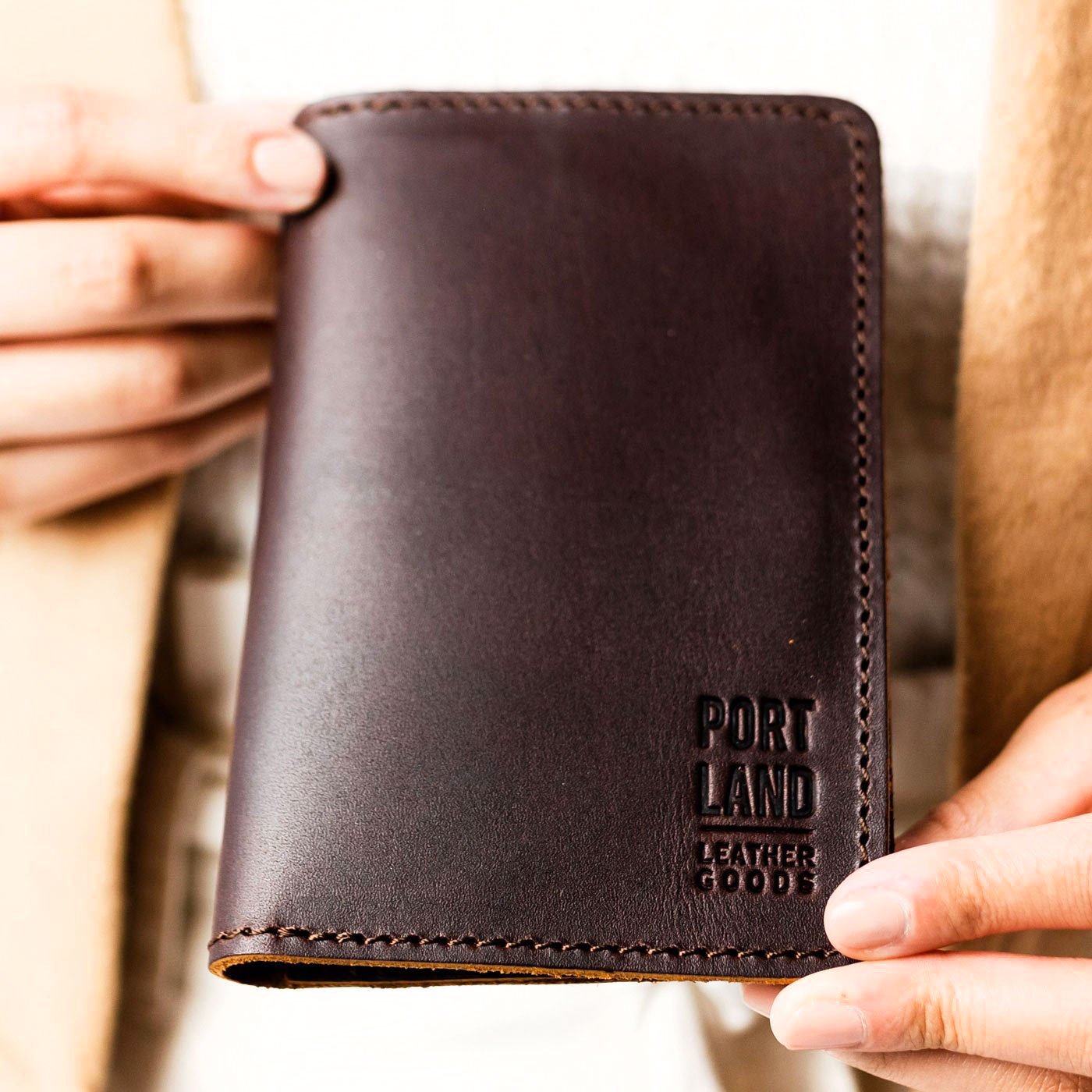 Grizzly | Model holding leather passport case with PLG logo