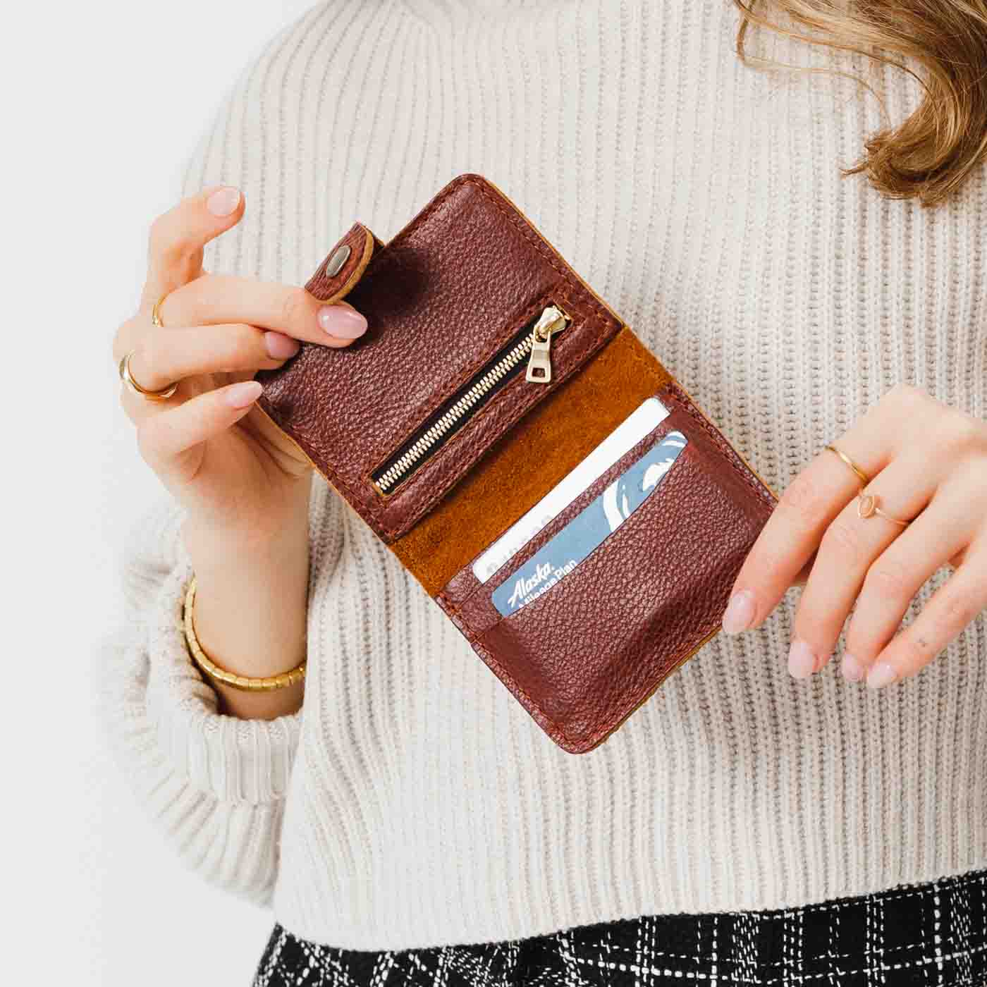 Nutmeg | Model holding small leather bifold wallet with snap open