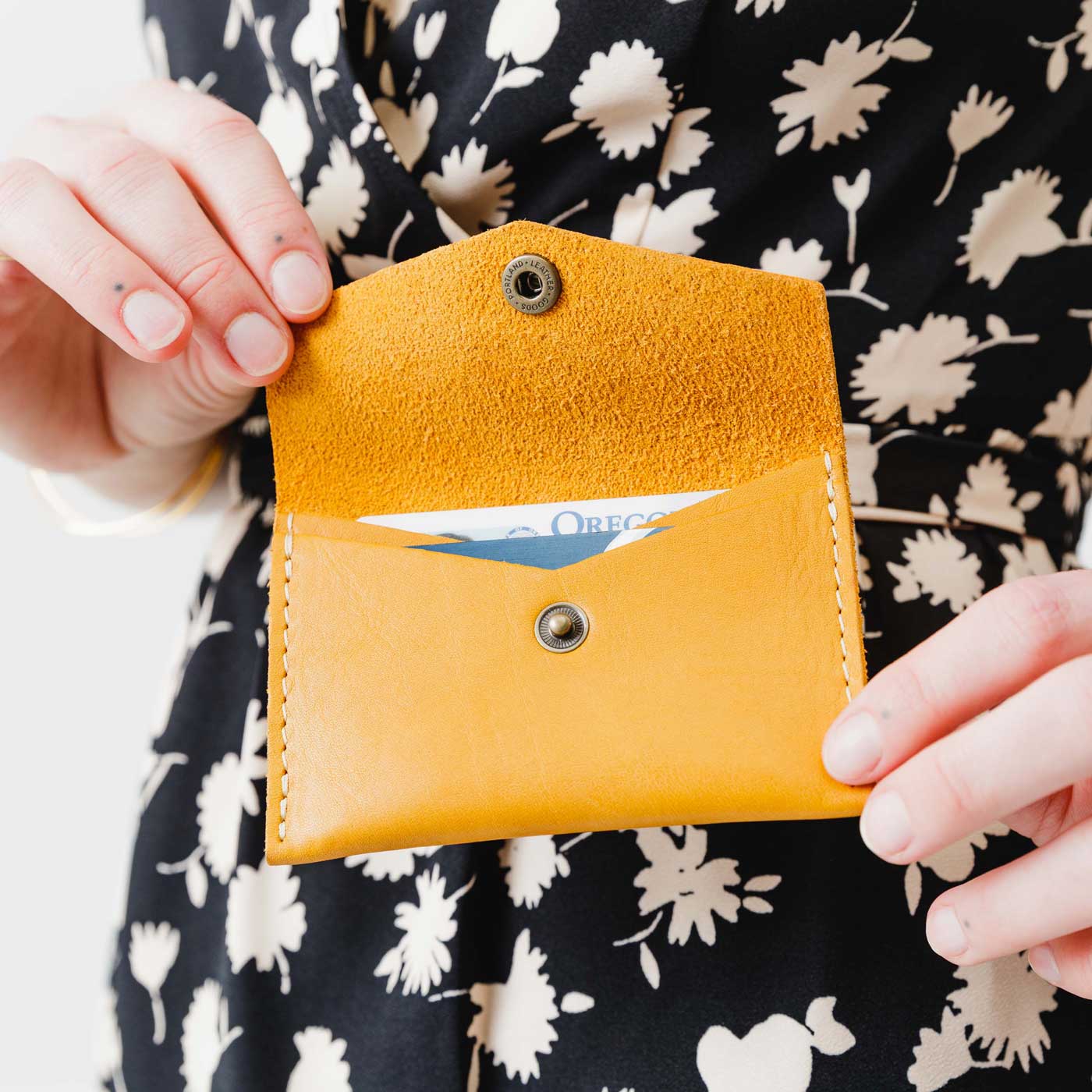 Sunflower | Model holding small leather envelope wallet with snap closure open